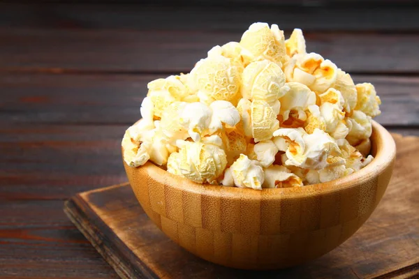 Solené popcorn v dřevěné misce na dřevěný stůl. — Stock fotografie