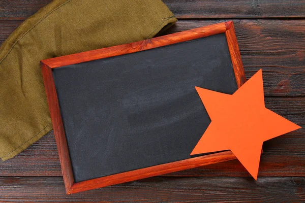 Pizarra con espacio vacío, gorra militar y estrella roja sobre una madera — Foto de Stock