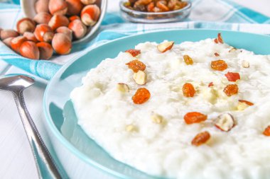 Pirinç sütü yulaf lapası ile fındık ve kuru üzüm bir WHI üzerinde mavi bir tabak içinde