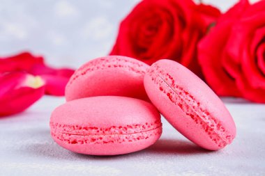 Pembe ve mor macaroons pembe ve beyaz çiçekler tarafından çevrili gri bir tablo.