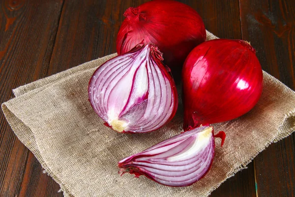 Fresh red onions and chopped slices on a wooden table. — Stock Photo, Image