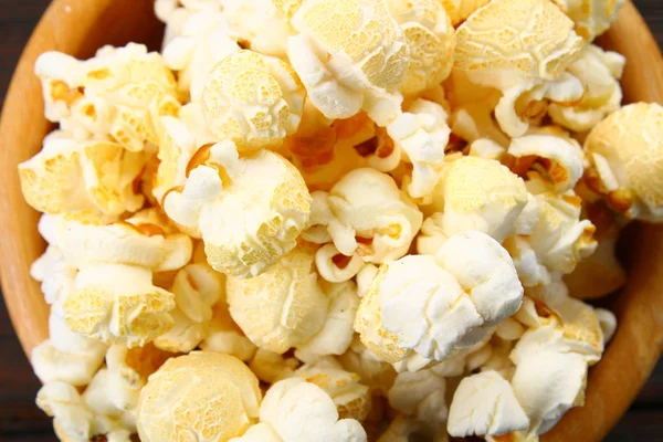 Solené popcorn v dřevěné misce na dřevěný stůl. — Stock fotografie