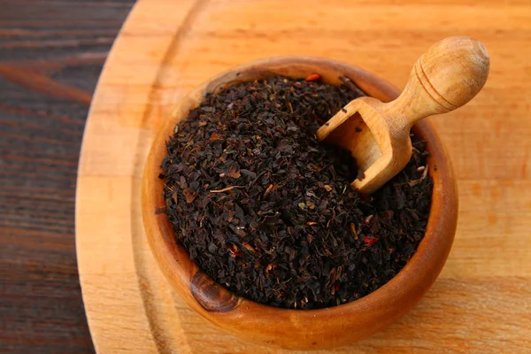 Μαύρο ξηρό τσάι με ένα κεράσι σε ένα μπολ σε ένα ξύλινο τραπέζι. — Φωτογραφία Αρχείου