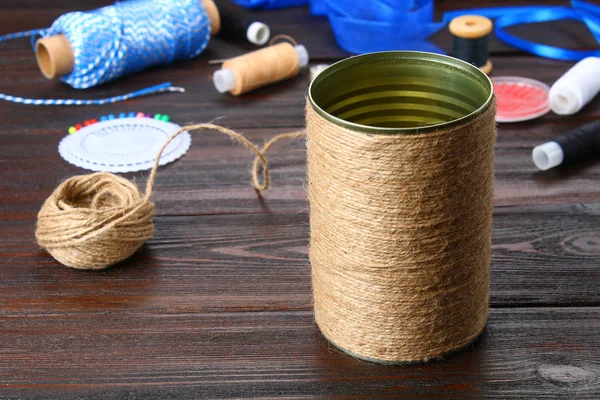 Hands wrapping an iron jar with a string on a wooden table. Hand — Stock Photo, Image