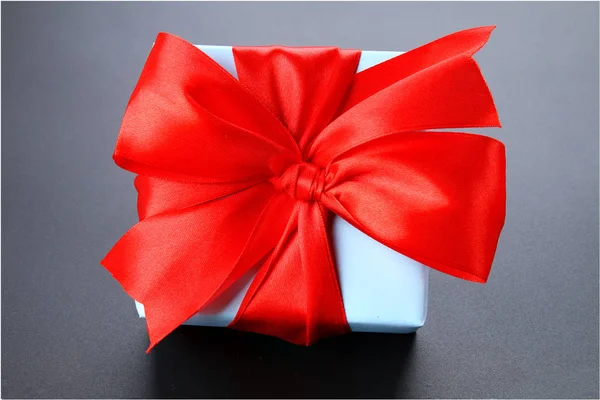 Cadeau blauwe doos met een rode strik op een grijze achtergrond. — Stockfoto