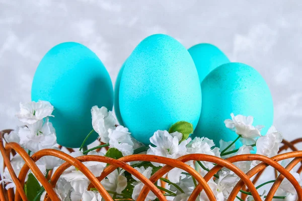 Œufs de Pâques colorés dans un panier sur un fond de béton gris . — Photo