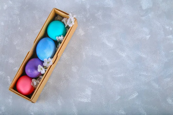 Huevos de Pascua de colores en una caja de regalo sobre un fondo de hormigón gris . — Foto de Stock