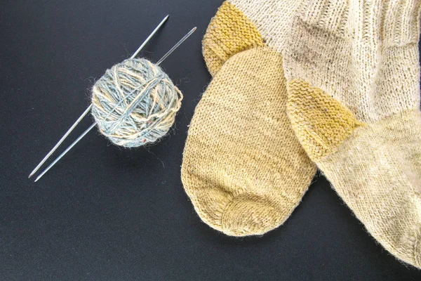 Ein Wollknäuel mit Stricknadeln und Socken auf einem grauen Tisch. Handarbeit. — Stockfoto