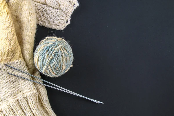 Ein Wollknäuel mit Stricknadeln und Socken auf einem grauen Tisch. Handarbeit. — Stockfoto