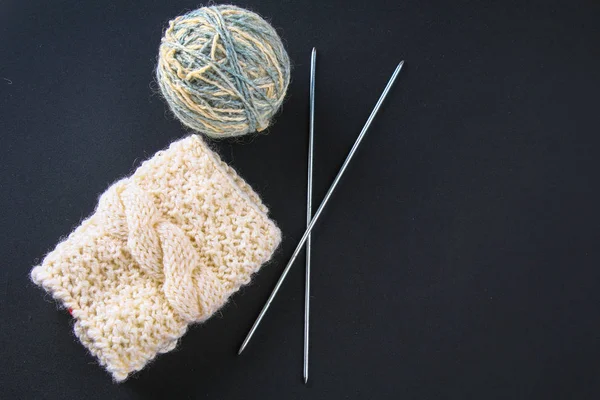 Ein Wollknäuel mit Stricknadeln und Socken auf einem grauen Tisch. Handarbeit. — Stockfoto