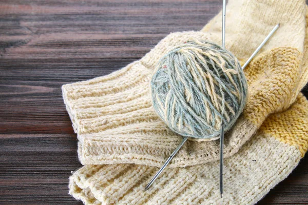 Ein Wollknäuel mit Stricknadeln und gestrickten Socken auf einem Holztisch. Handarbeit. — Stockfoto