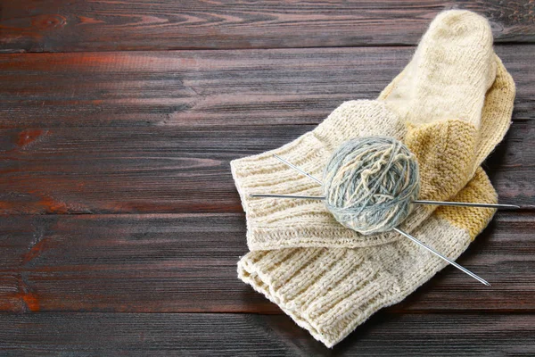 Ein Wollknäuel mit Stricknadeln und gestrickten Socken auf einem Holztisch. Handarbeit. — Stockfoto