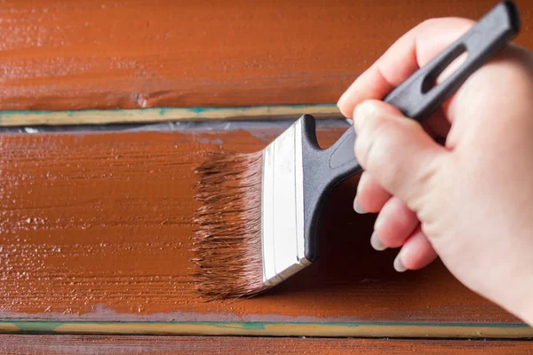 Escova com tinta na mão. Um homem pinta placas azuis em um pincel de tinta marrom . — Fotografia de Stock