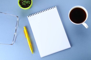 Üstten Görünüm görüntüsü açık defter ile boş sayfaları ve mavi arka plan, eklemek için hazır veya sahte kadar kahve. Natürmort, iş, ofis, banka donatımı veya eğitim kavramı.