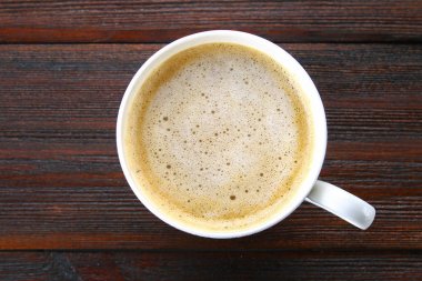 Bir fincan kapuçino ahşap masa üzerinde Üstten Görünüm.