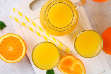 Cam bardak ve bir sürahi taze portakal suyu üzerine gri masa lambası turuncu ve sarı renkli boruları dilimleri ile.