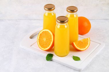 Cam şişe portakal dilimleri ve gri masa lambası üzerine sarı boruları ile taze portakal suyu ile.