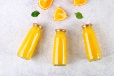 Cam şişe portakal dilimleri ve gri masa lambası üzerine sarı boruları ile taze portakal suyu ile. Üstten Görünüm. Düz Lay.