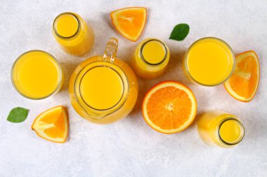 Cam şişeler, gözlükleri ve bir sürahi taze portakal suyu üzerine gri masa lambası turuncu ve sarı renkli boruları dilimleri ile. Üstten Görünüm. Düz Lay.