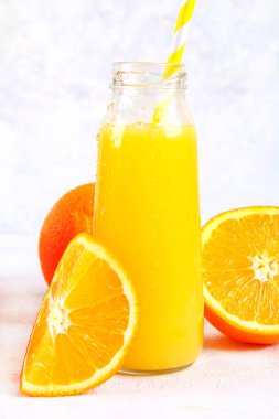 Şişe taze portakal, elma, domates suyu ve renkli tübüllerin bir gri beton tablo ile.