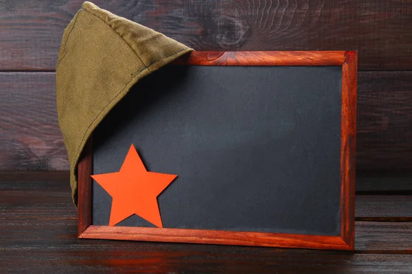 Chalkboard com espaço vazio, boné militar e estrela vermelha em uma madeira — Fotografia de Stock