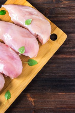 Çiğ tavuk fileto kesme tahtası ahşap bir masa arka planı. Et yemek pişirmek için malzemeler. Bir yazıt için boş yer. Uzay kopyalayın. Düz lei. Üstten Görünüm.