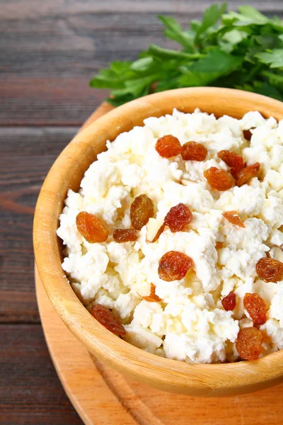 Ricotta fatta in casa con mandorle e uvetta in una ciotola su un tavolo di legno . — Foto Stock