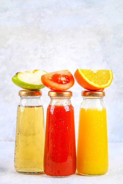 Botellas con naranja fresca, manzana, jugo de tomate sobre una mesa de hormigón gris. Lobulillos Frutas y verduras alrededor. Vista superior. Piso Lay . — Foto de Stock