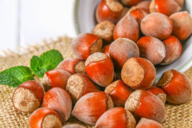 Beyaz ahşap bir masa üzerinde çul üzerinde dağınık ceviz fındık.