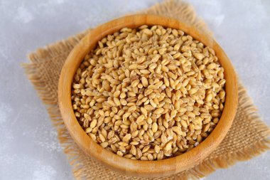 Bir gri beton masada ahşap bir kase kuru pearl arpa.