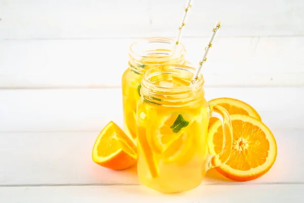 Orange detox water in mason jars on a white wooden table. Healthy food, drinks. — Stock Photo, Image