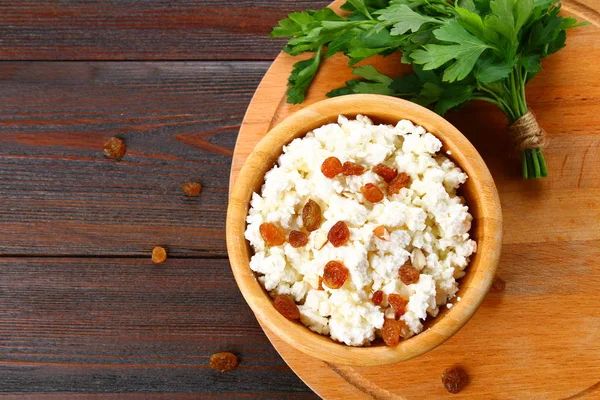 Ricotta fatta in casa con mandorle e uvetta in una ciotola su un tavolo di legno . — Foto Stock