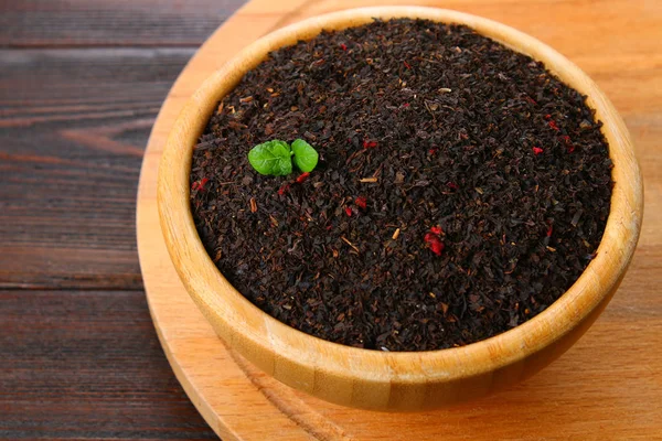 Tè secco nero con una ciliegia in una ciotola su un tavolo di legno . — Foto Stock