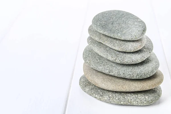 From spa stones make Balances pyramids on white wooden background.