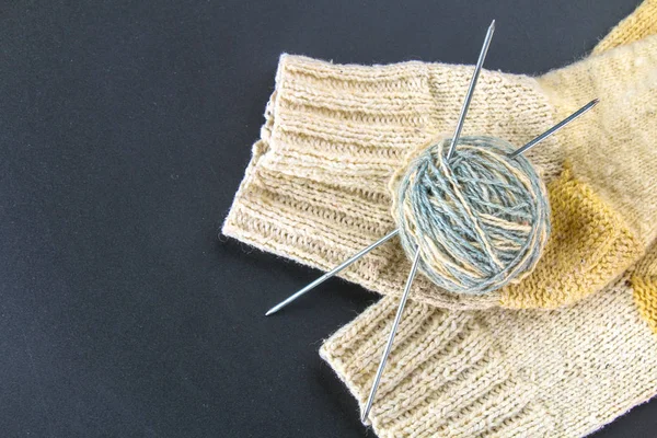 Una palla di lana con ferri da maglia e calzini su un tavolo grigio. Lavori ad ago . — Foto Stock