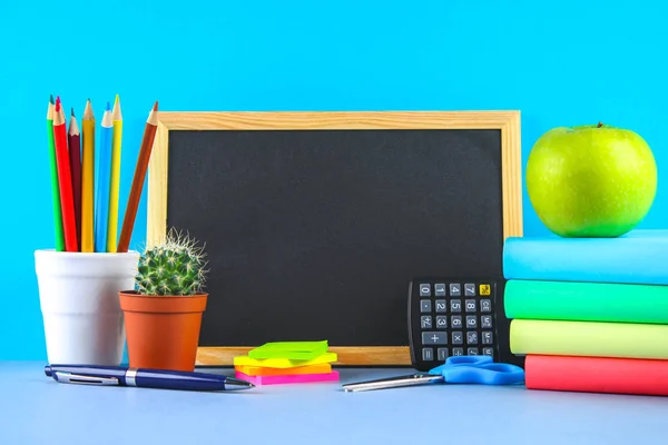 Uma pilha de livros e artigos de papelaria sobre um fundo de quadro. Mesa de trabalho, educação, escola . — Fotografia de Stock