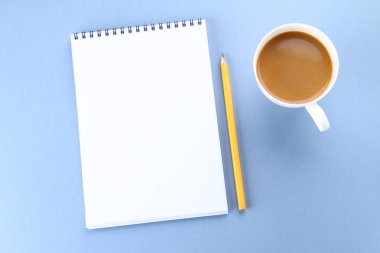 Üstten Görünüm görüntüsü açık defter ile boş sayfaları ve mavi arka plan, eklemek için hazır veya sahte kadar kahve. Natürmort, iş, ofis, banka donatımı veya eğitim kavramı.