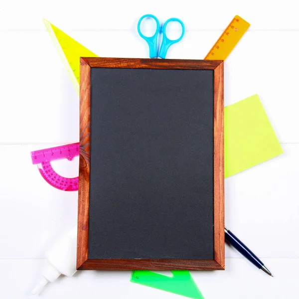 Chalkboard cercado por artigos de papelaria em uma mesa de madeira branca. Copie o espaço . — Fotografia de Stock