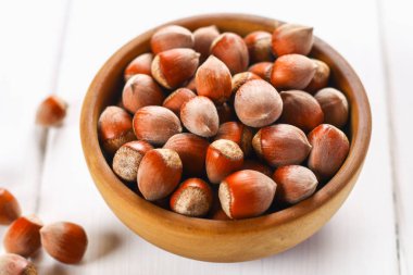 Beyaz ahşap bir masa üzerinde bir ahşap kase fındık fındık. Superfood.