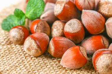 Beyaz ahşap bir masa üzerinde çul üzerinde dağınık ceviz fındık.