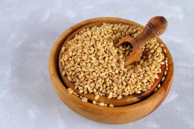 Bir gri beton masada bir kepçe ile ahşap bir kase kuru pearl arpa.