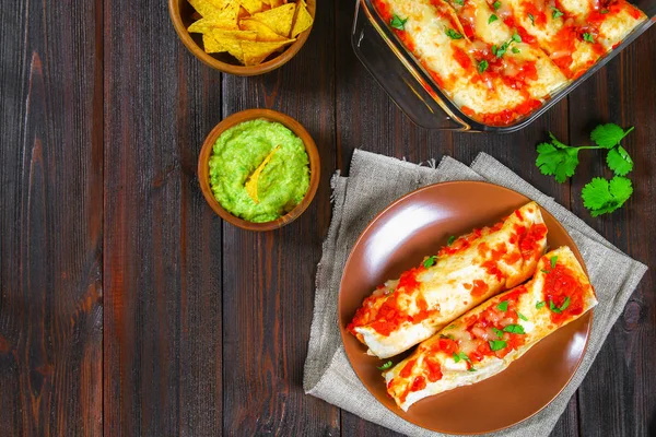 Zelfgemaakte kip enchiladas in schotel op houten tafel. Bovenaanzicht. — Stockfoto
