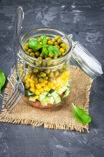 Healthy homemade salad in a jar with vegetables, cucumbers, tomatoes, peas and corn - Healthy diet, detox, pure food or vegetarian concept.
