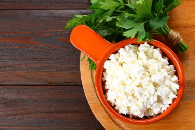 Ahşap bir masa üzerinde bir kasede ev süzme peynir.