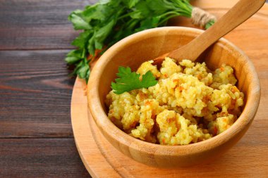 Pirinç pilavı tavuk, baharat ve maydanoz ahşap bir masa üzerinde bir kase ile.