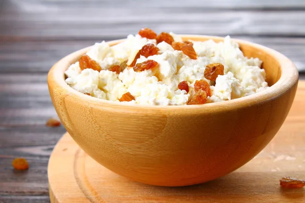 Queso casero con almendras y pasas en un tazón sobre una mesa de madera . — Foto de Stock