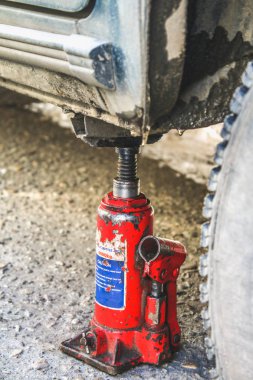 Kırmızı bir jack delinmiş tekerlek değiştirmek için araç asansörleri.