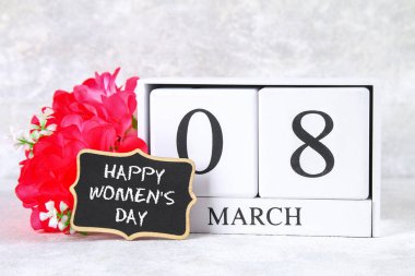 8 Mart Dünya Kadınlar Günü. Ahşap sonsuz takvim, pembe çiçekler ve yazı tahtası.