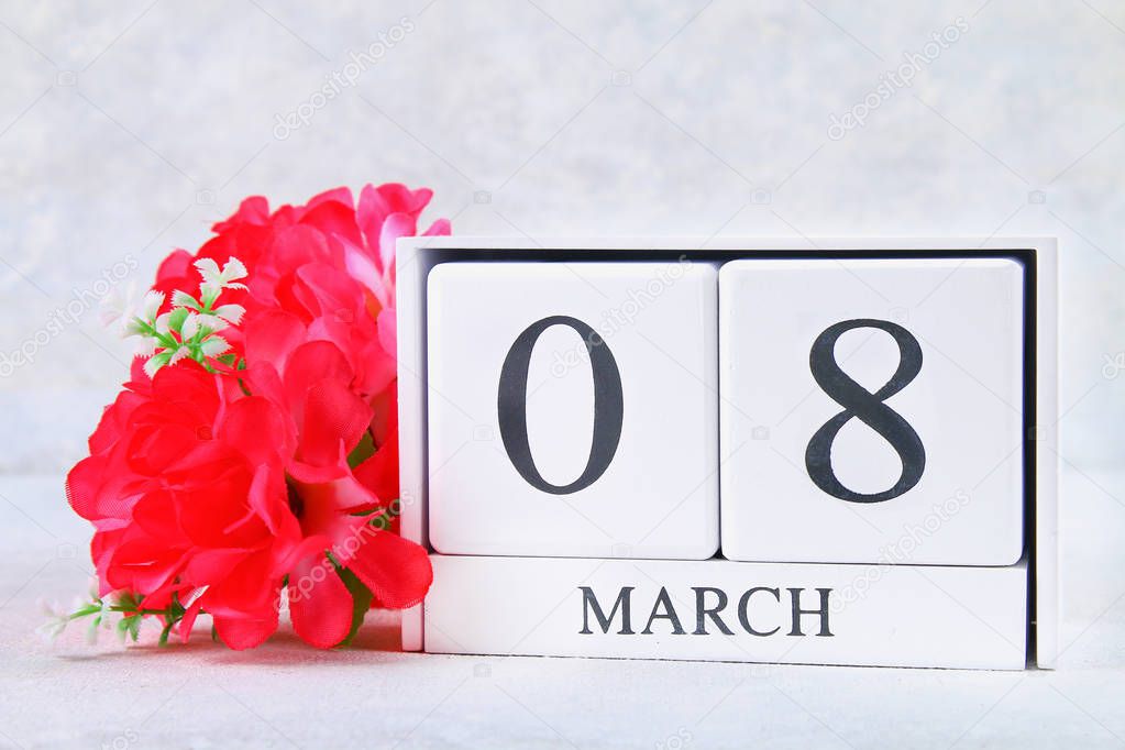 March 8, International Women's Day. Wooden perpetual calendar and pink flowers.