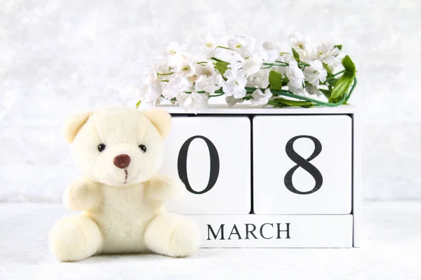 8 Mart Dünya Kadınlar Günü. Ahşap bir sonsuz takvim ve beyaz çiçekler, oyuncak ayı. — Stok fotoğraf